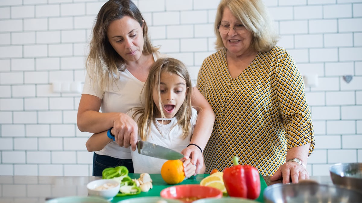 Three generations preparing a meal together in a cozy kitchen setting.