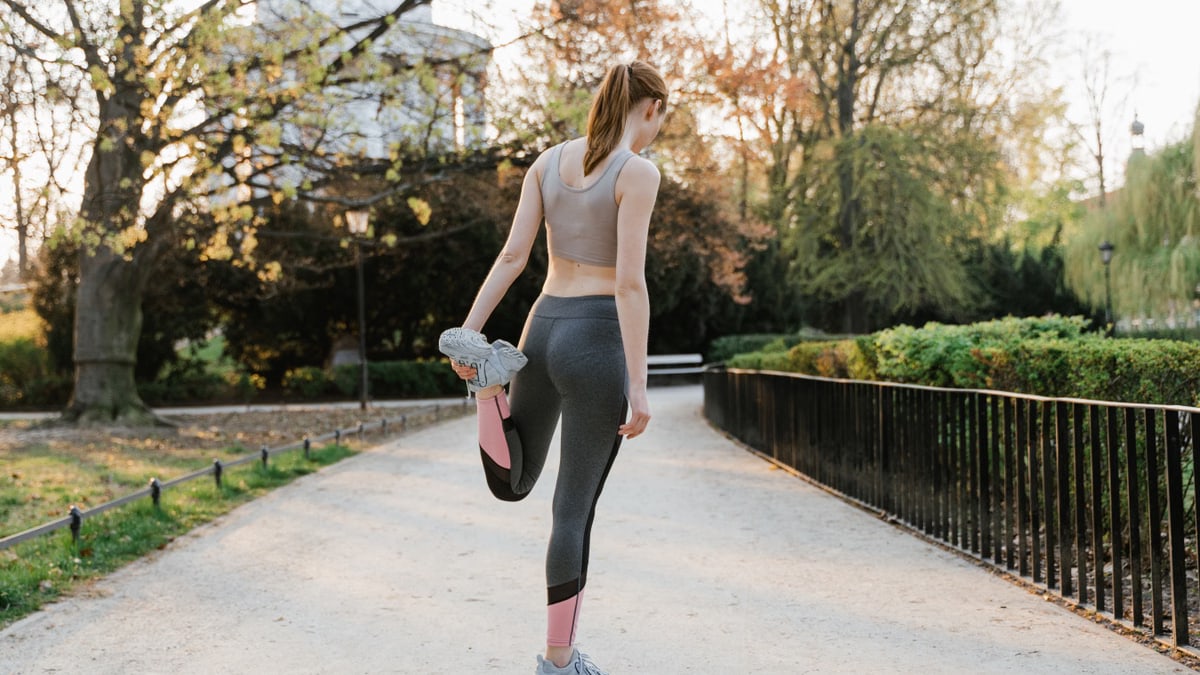 Woman in sportswear stretches in a sunny park, promoting fitness and wellness.